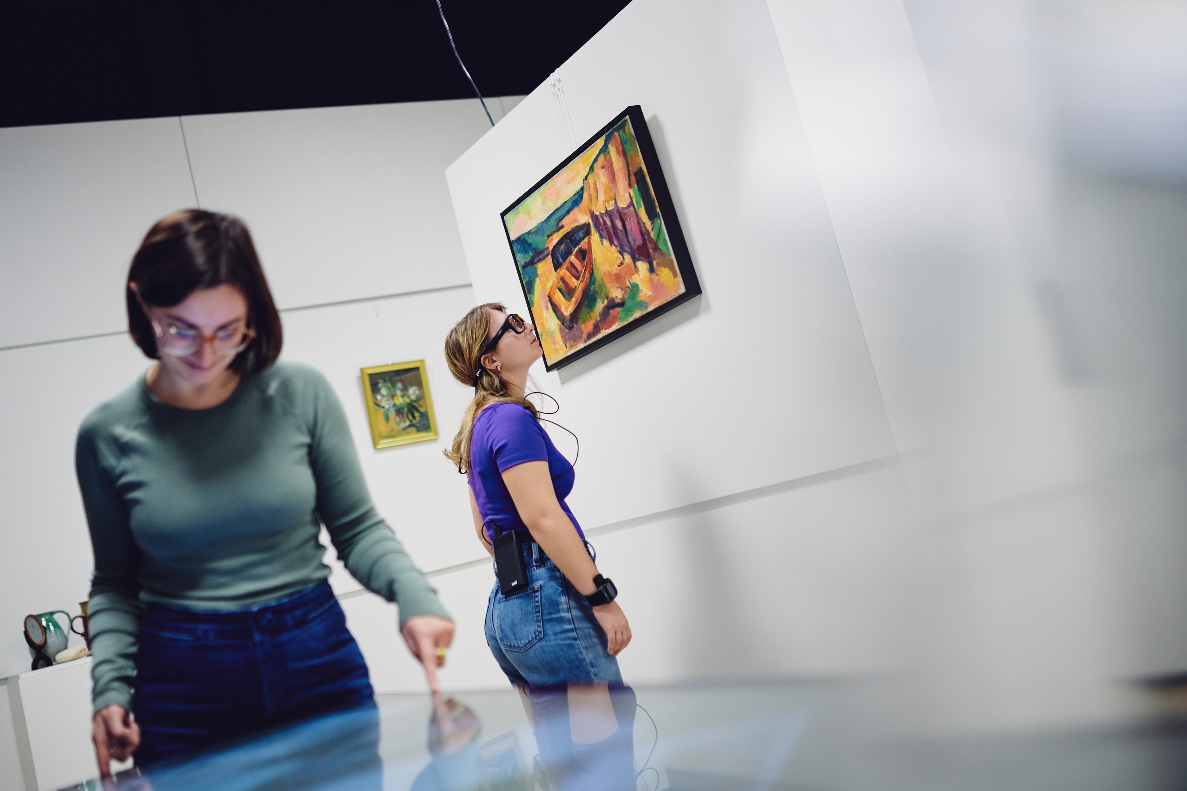Im Vordergrund eine Person an einem Multi-Touch-Tisch, Person hinten blickt Gemälde an