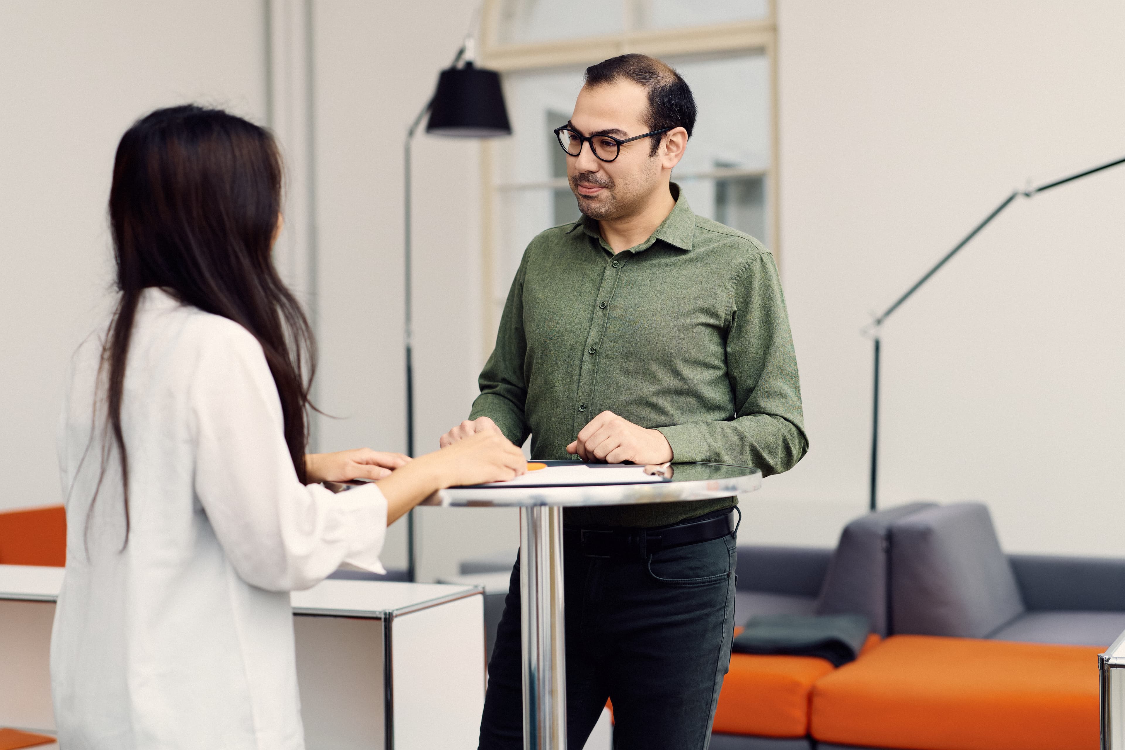 Zwei IWM Mitarbeitende unterhalten sich an einem Stehtisch