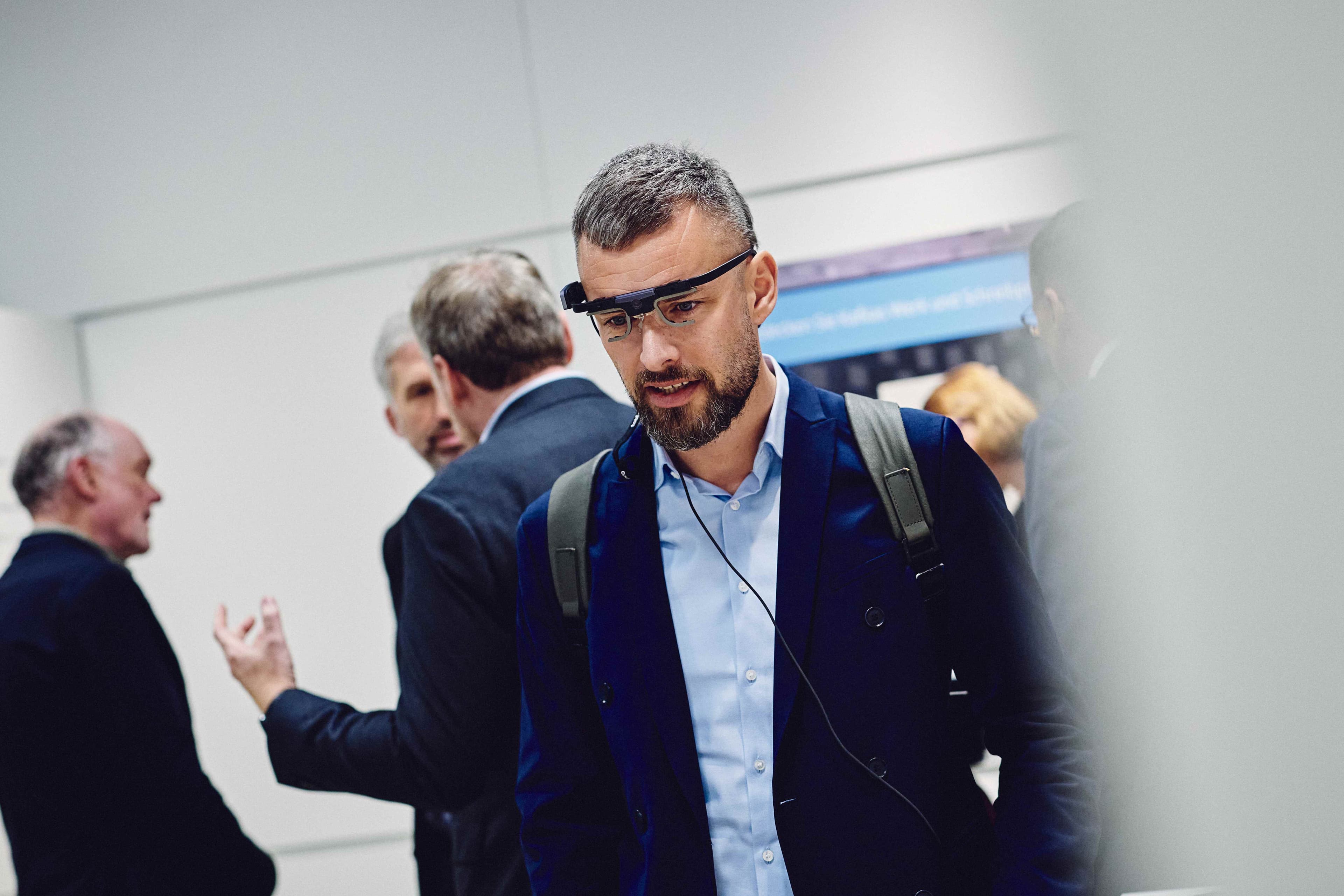 Ein Gast testet mit einer Datenbrille eine interaktive Anwendung im MuseumLab. Weitere Besucherinnen und Besucher befinden sich im Hintergrund