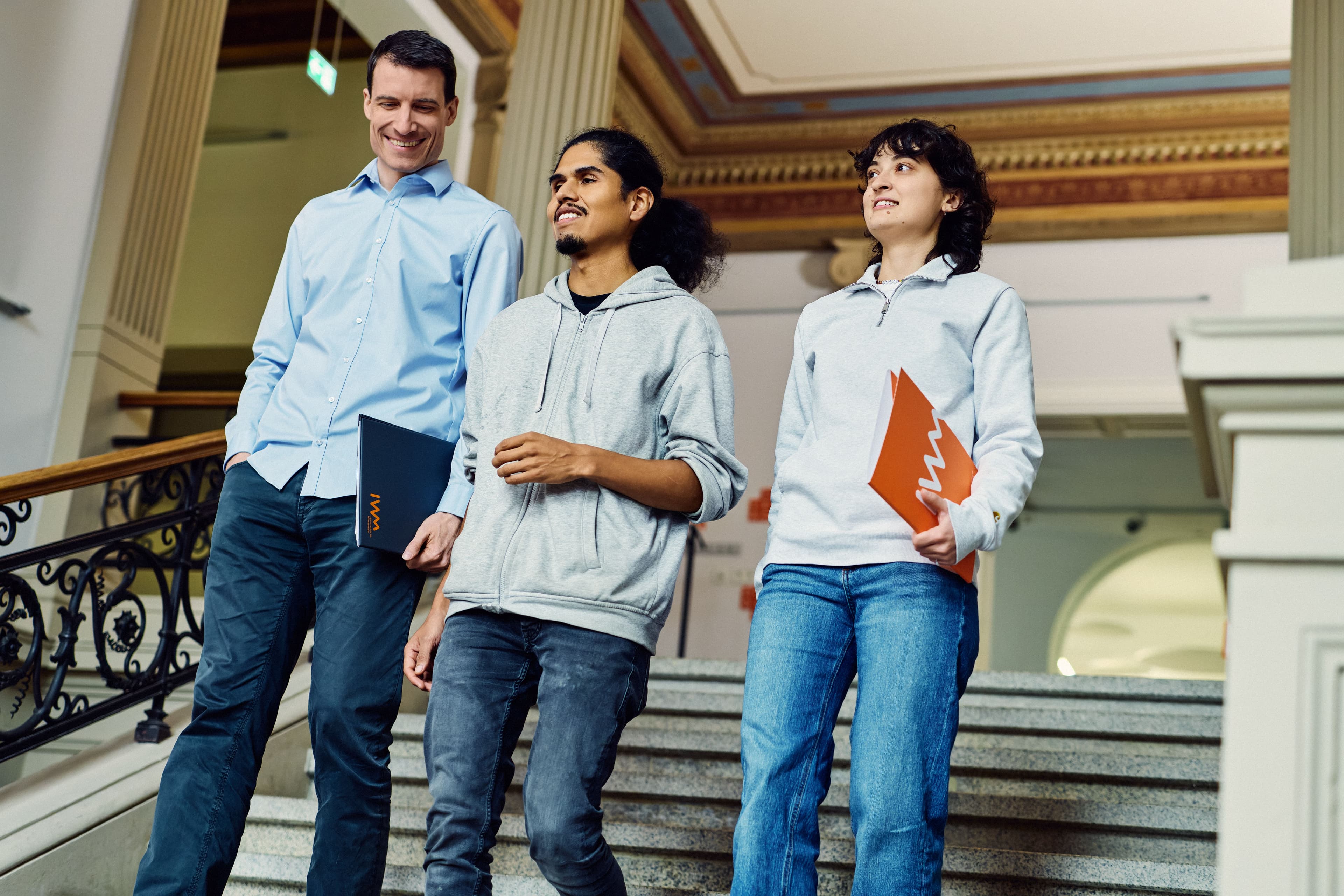 Drei IWM-Mitarbeitende laufen gemeinsam eine Treppe herunter