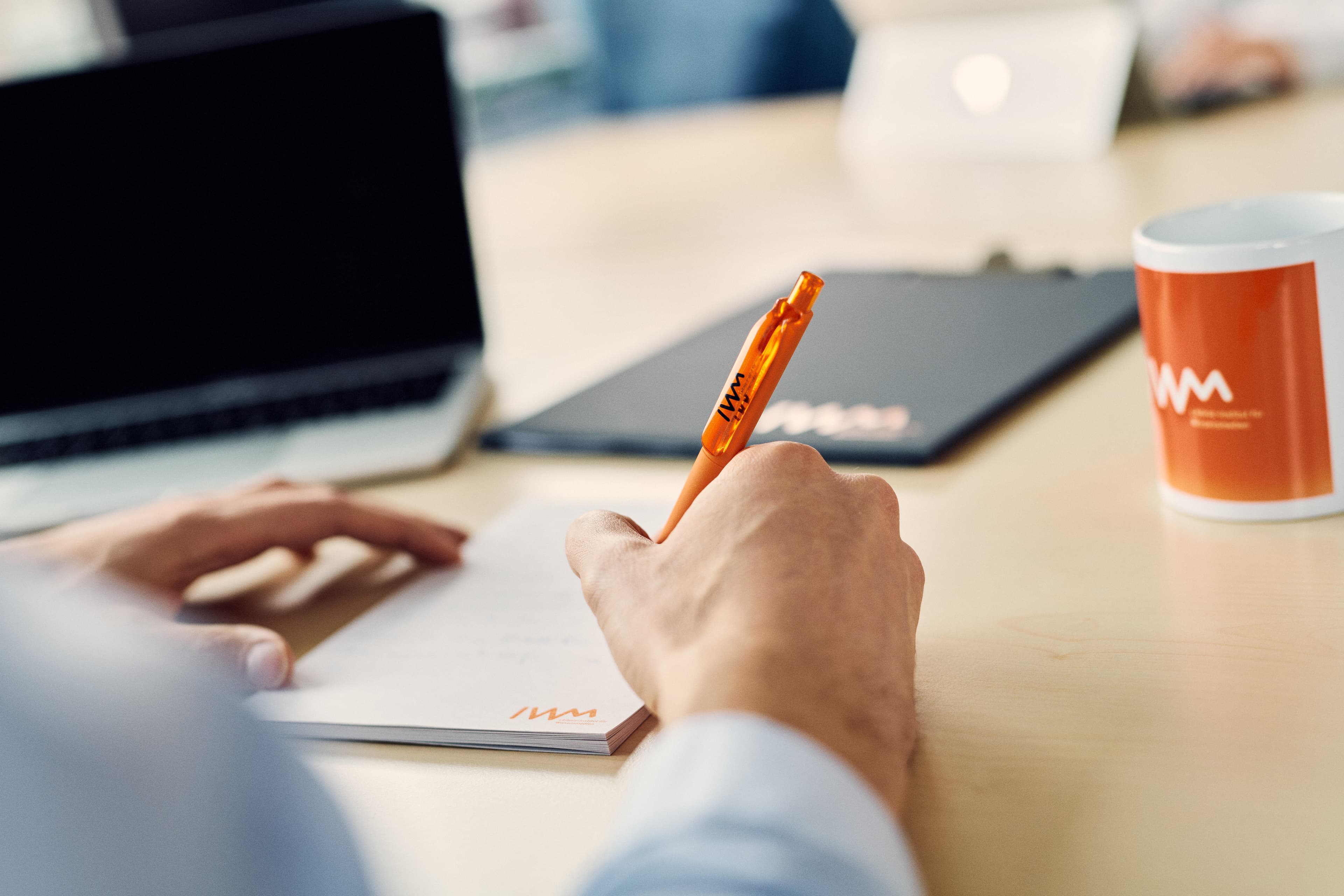 Eine Person schreibt Notizen auf einen IWM-Block