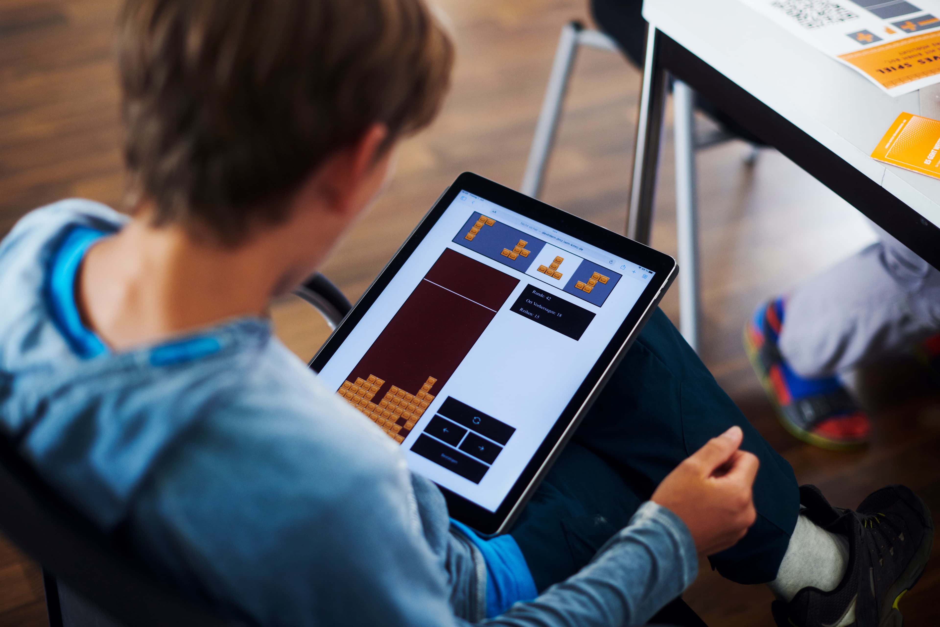 Eine Person sitzt auf einem Stuhl und bedient ein Tablet